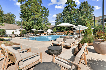 a swimming pool with lounge chairs and umbrellas at Caveness Farms Apartments, Wake Forest, NC 27587